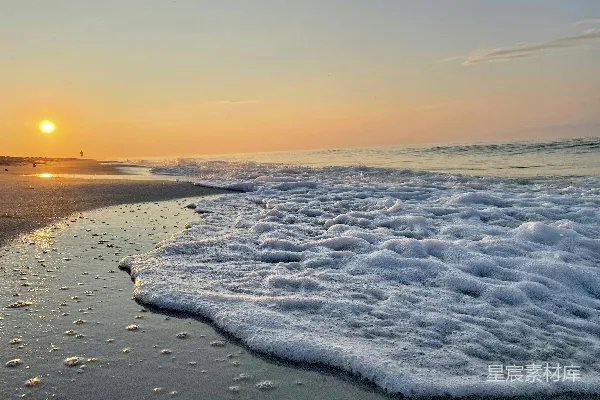 高清摄影 夕阳正沉落在海面上，波浪不断涌来。