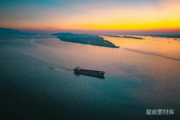 高清摄影 货船在平静的水面上行驶，夕阳西下。