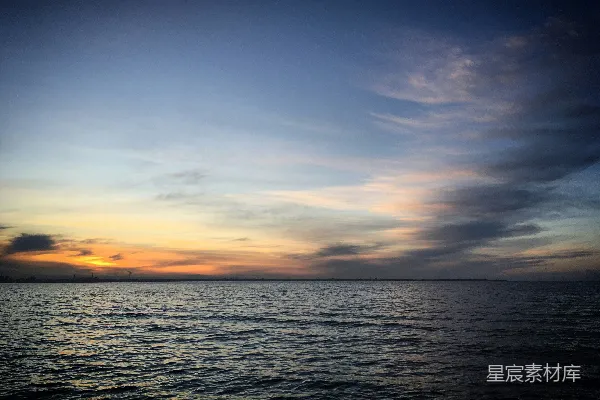 高清摄影 夕阳映照在水面上，天空中飘着云彩。