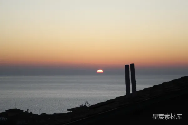 高清摄影 夕阳映照在海面上，屋顶的轮廓在天空中映衬而出。