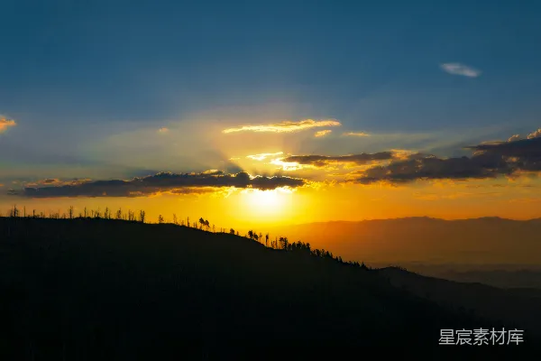高清摄影 夕阳正在山丘上落下，山丘上长满了树木。