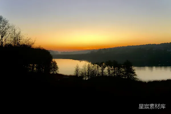 高清摄影 夕阳西下，湖面上树木倒映其中。