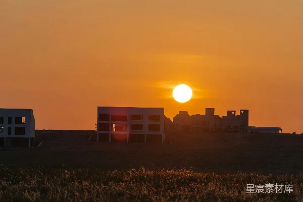 高清摄影 夕阳西下，草地上未完工的建筑物。