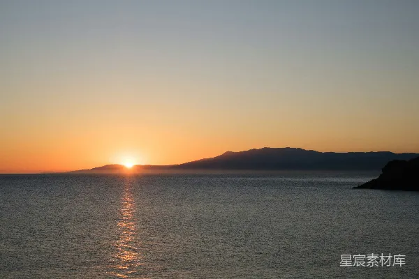 高清摄影 夕阳映照在海面上，远处的山脉若隐若现。