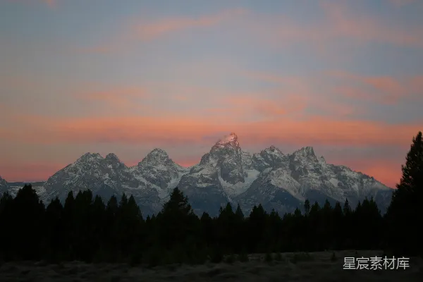 高清摄影 在山脉的夕阳景色中，前景中有树木。
