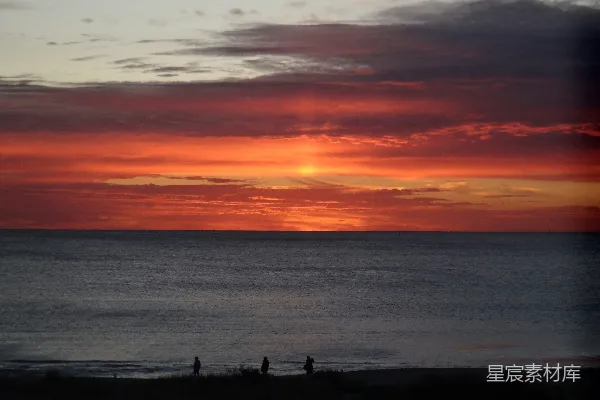 高清摄影 夕阳映照在海面上，人们在海滩上散步