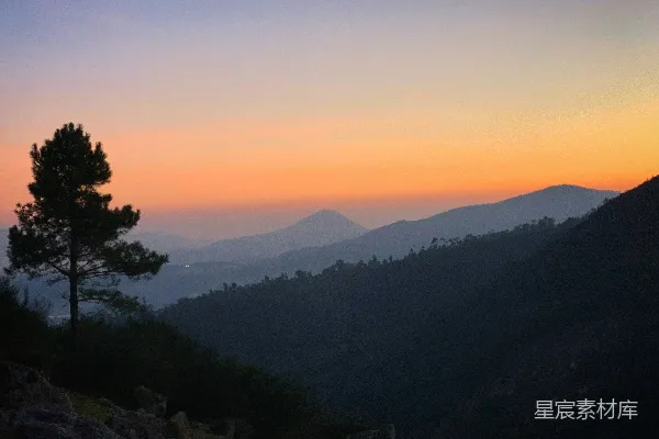 高清摄影 一棵孤独的树在群山之上绚丽的夕阳映衬下剪影。