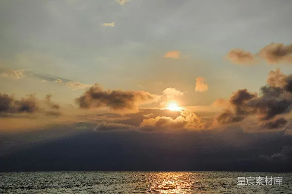 高清摄影 在一个多云的天气里，夕阳正照耀着海面。