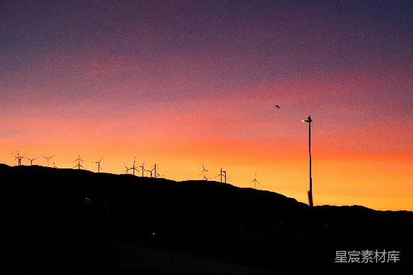 高清摄影 夕阳西下，远处的山坡上有许多风力发电机。