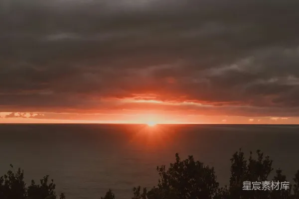 高清摄影 夕阳映照海面，天空阴沉，乌云密布。