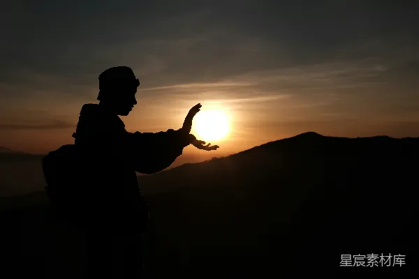 高清摄影 在日落时分，站在山顶上的男子剪影。