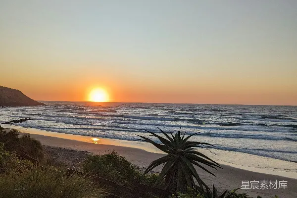 高清摄影 夕阳正在海面上落下，照在沙滩上。