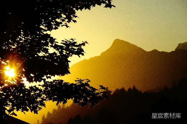 高清摄影 夕阳金辉映照着剪影中的山峦和树木。