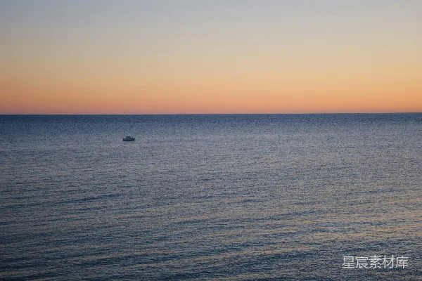 高清摄影 一艘小船在平静的海面上，夕阳西下。