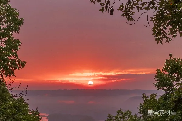 高清摄影 夕阳正笼罩着一个树木环绕的山谷。