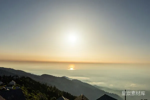 高清摄影 雾蒙蒙的山峦上初升的朝阳与散布的房屋。