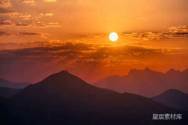 高清摄影 金黄色的夕阳落在剪影中的山峰后面。