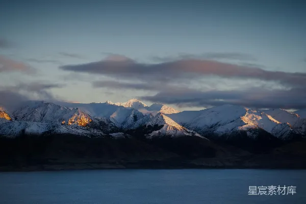 高清摄影 雪山倒映在宁静的水面上，阳光洒在上面。