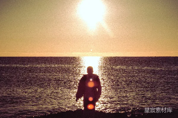 高清摄影 穿着黑色潜水服的男人站在海滩上，夕阳西下。