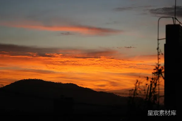 高清摄影 绚丽的夕阳天空映衬着剪影的山脉和建筑物。