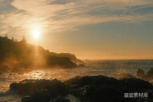高清摄影 落日余晖洒在岩石海岸上，海浪翻滚。