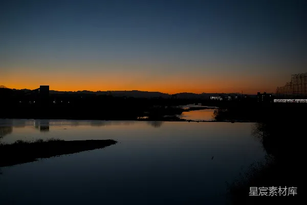 高清摄影 夕阳的余晖洒在平静的河面上，远处的城市天际线清晰可见。