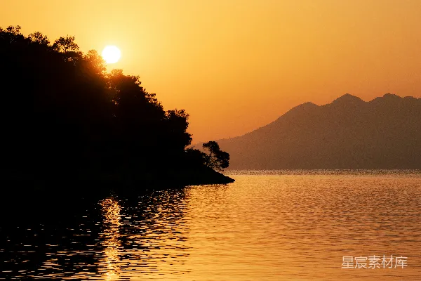 高清摄影 夕阳西下，湖面倒映着远处的山峦。