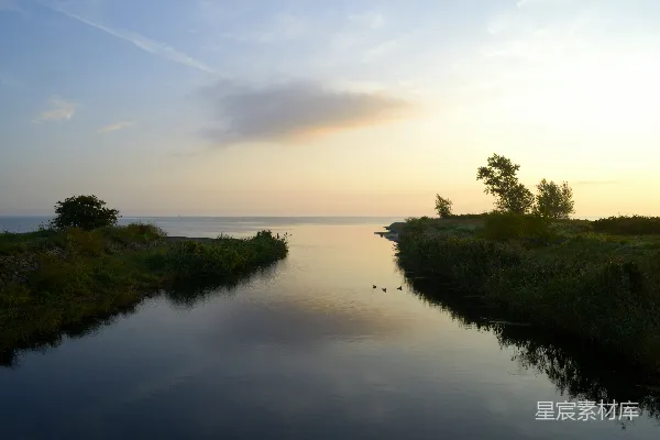 高清摄影 宁静的河流在夕阳下流入一片宁静的海洋。
