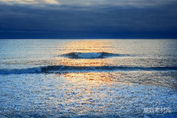 高清摄影 海浪拍打着岩石海岸，夕阳西下。