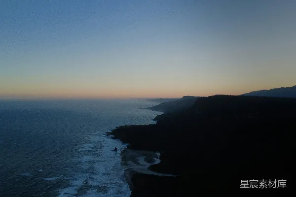 高清摄影 在黄昏时分，海浪拍打着一片黑暗而崎岖的海岸线。