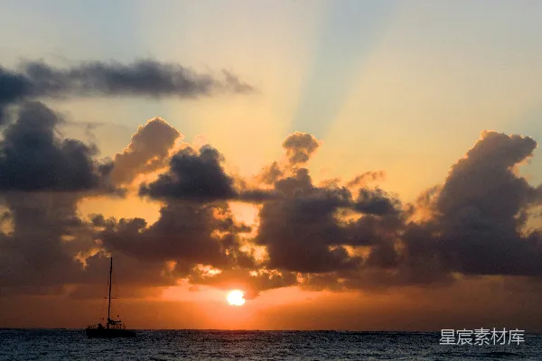 高清摄影 夕阳正落下海面，前景中有一艘帆船。