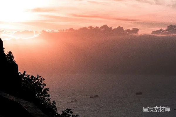 高清摄影 夕阳下，阳光穿透云层洒在海洋上，几艘船在海面上航行。