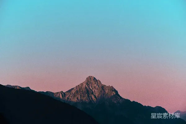 高清摄影 一座山峰，背景是粉红色的天空。