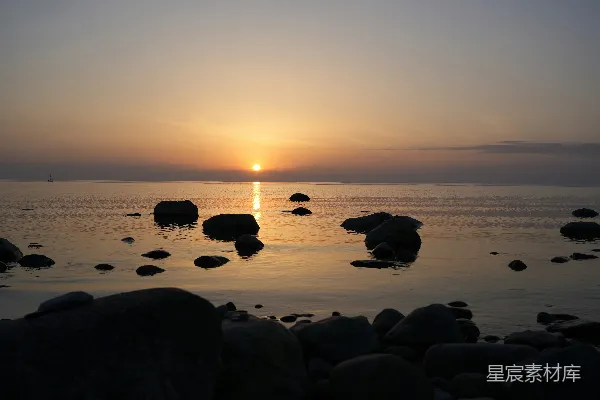 高清摄影 平静的海面映着宁静的落日，散布着几块暗色的岩石。