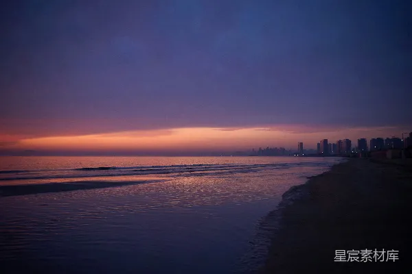 高清摄影 海滩上的日落景色，背景中有建筑物。