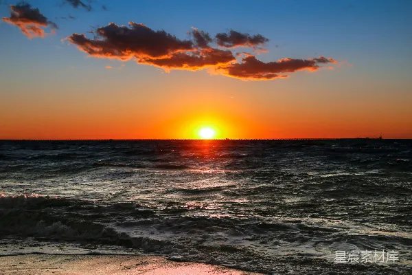 高清摄影 夕阳映照在海洋之上，远处有一艘船。
