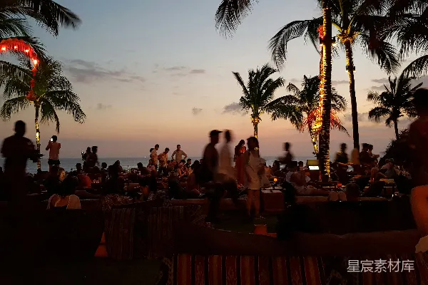 高清摄影 一群人在日落时分坐在海滩上。