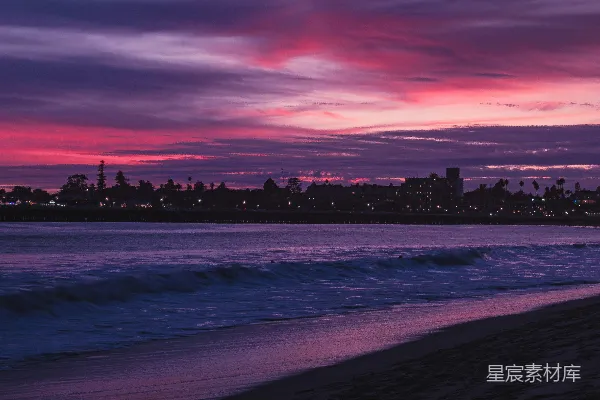 高清摄影 夕阳下的海滩美景，背景中可以看到城市。