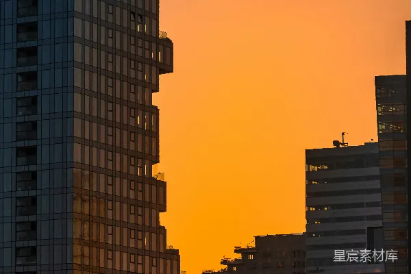 高清摄影 一列黄色的火车在夕阳下穿过高楼大厦。