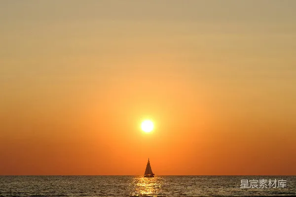高清摄影 夕阳正挂在海面上，前景中有一艘帆船。