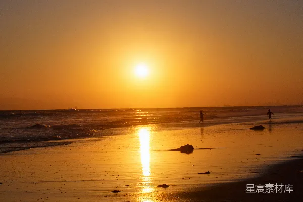 高清摄影 夕阳正映在海面上的海滩上。