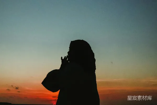 高清摄影 一个站在海滩上的人在夕阳下。