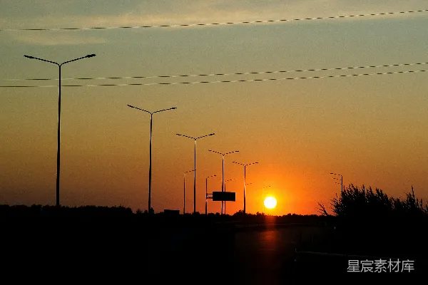 高清摄影 夕阳在远处的路灯后面落下。