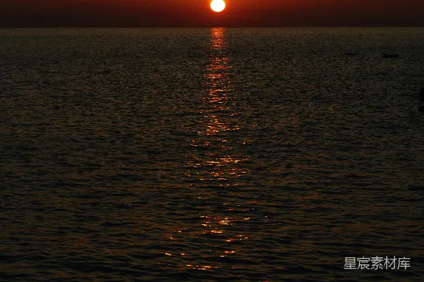 高清摄影 夕阳正从海面落下，一艘小船在水中漂浮。