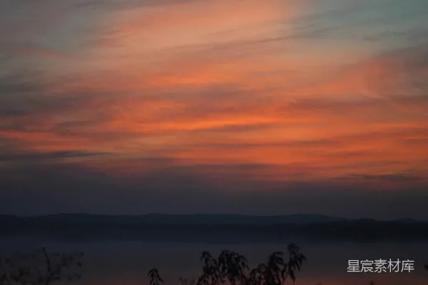 高清摄影 一幅夕阳的景象，远处有云和山脉。