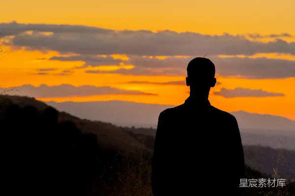高清摄影 一个男人站在夕阳下的山顶上。