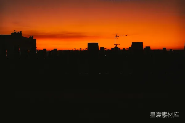 高清摄影 夕阳下城市的剪影，远处有一台起重机。