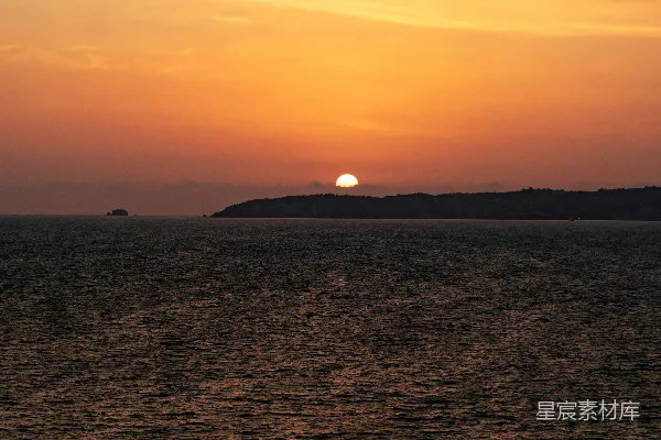 高清摄影 夕阳在一片水域上空，远处有一座小岛。