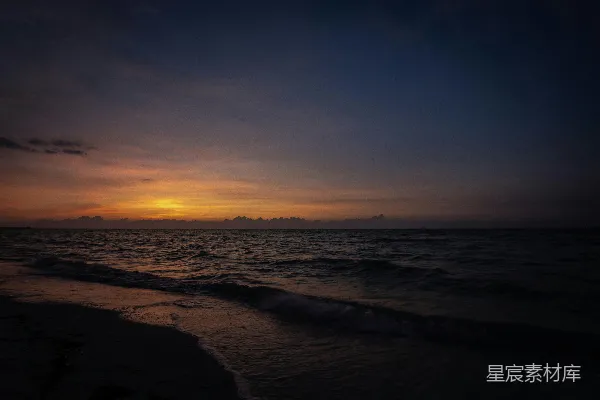 高清摄影 海面上的日落景象，波浪涌向岸边。