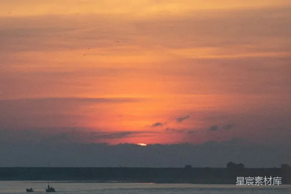 高清摄影 夕阳映照在水面上，远处有一艘小船。